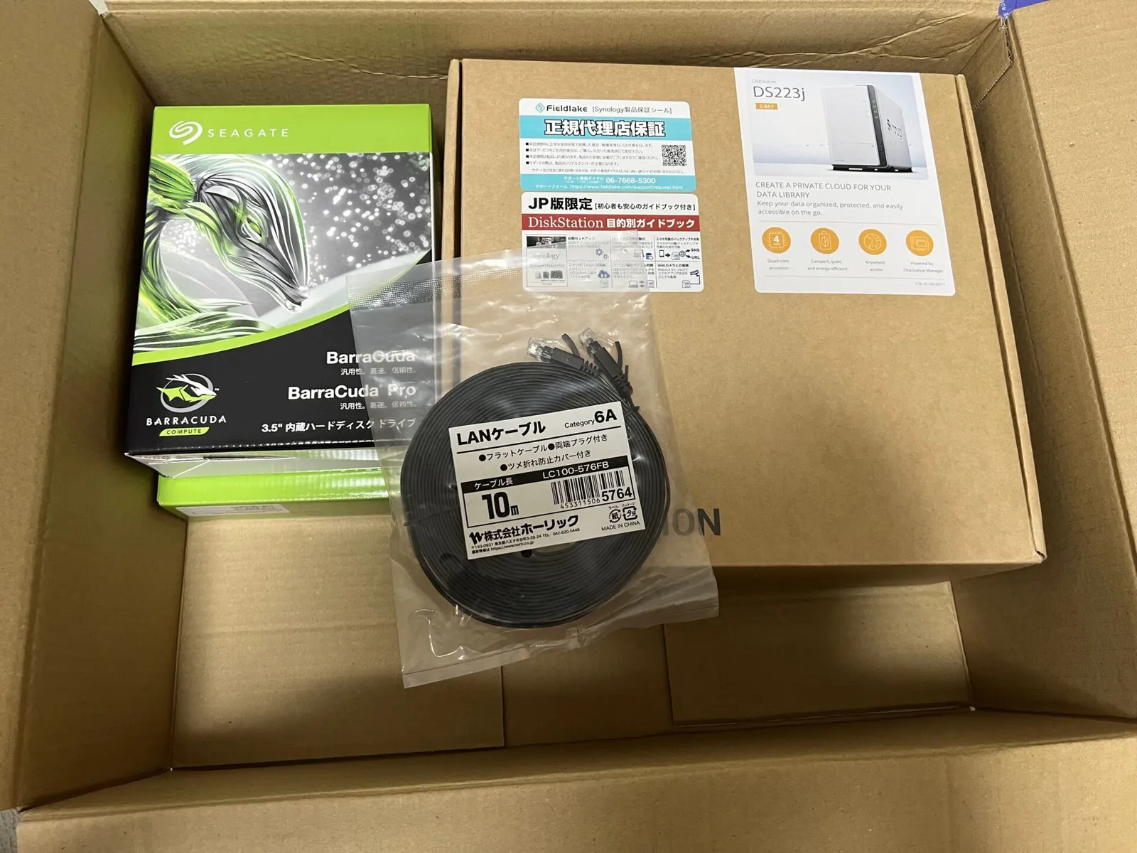段ボール箱に入ったDS223jの箱とSeagate BarraCudaのHDD、10mのLANケーブル