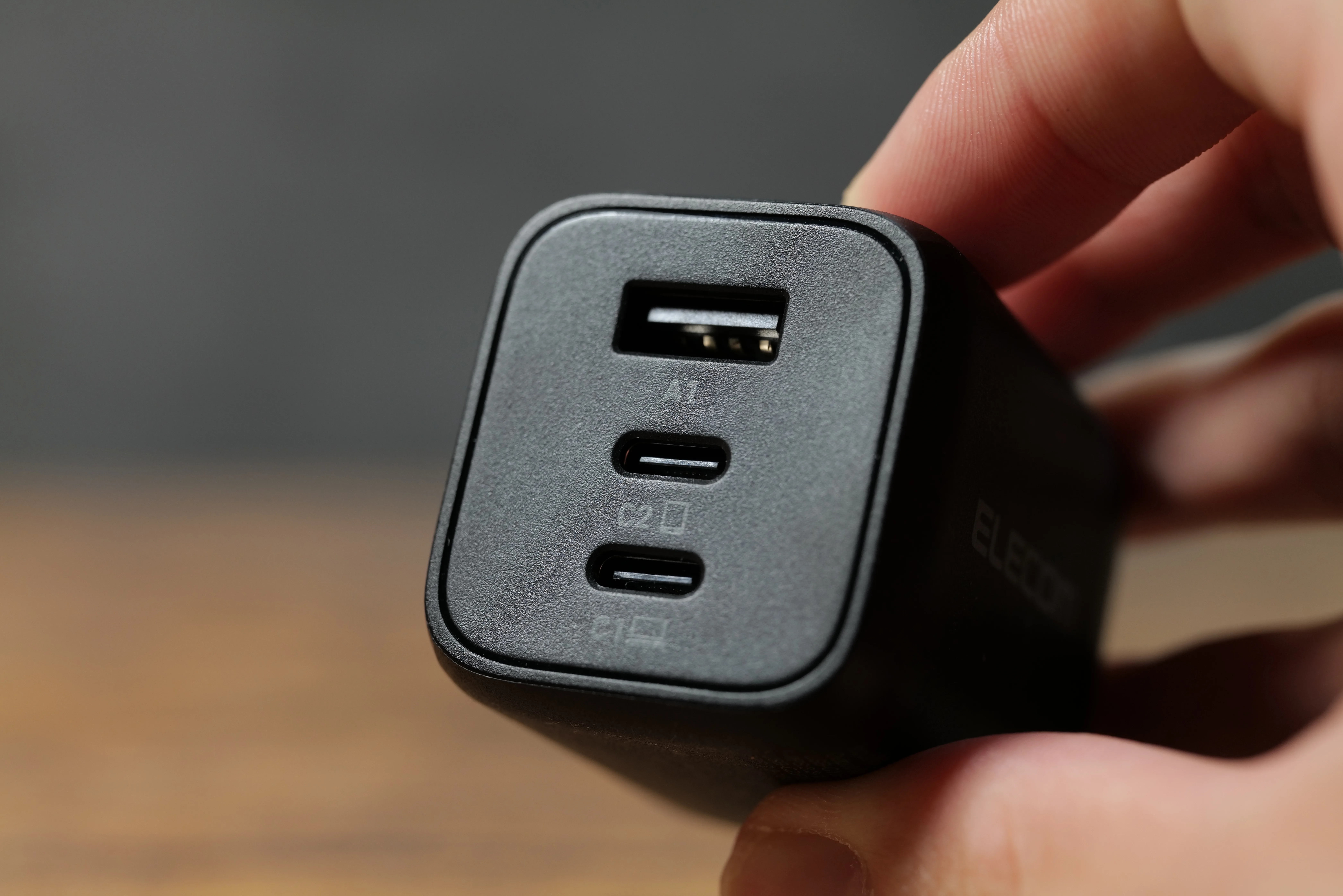 手に持ったエレコム EC-AC4465BKのポート面（USB-Aが1つ、USB Type-Cが2つ）