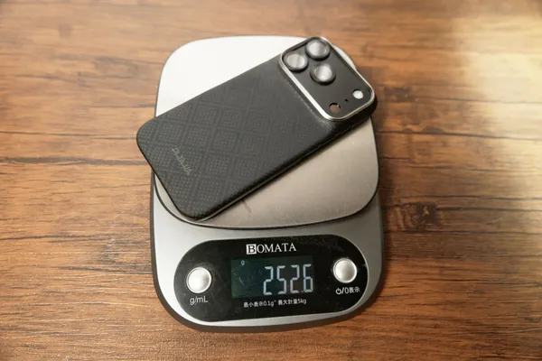 PITAKA Edge Caseを装着したiPhone 18 Proを量りで計測している様子。表示は252.6g