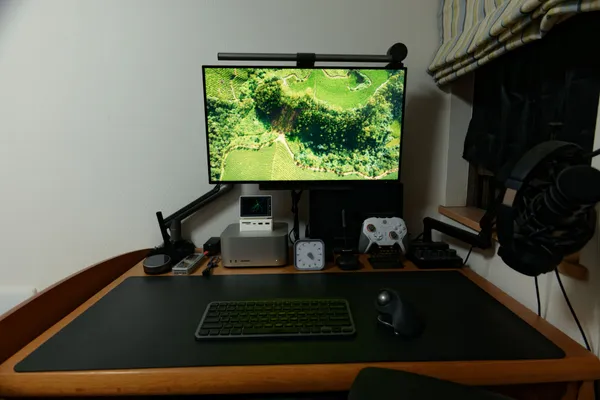 モニターライトをオフにしたデスク。手元のキーボードとデスクマットが暗い