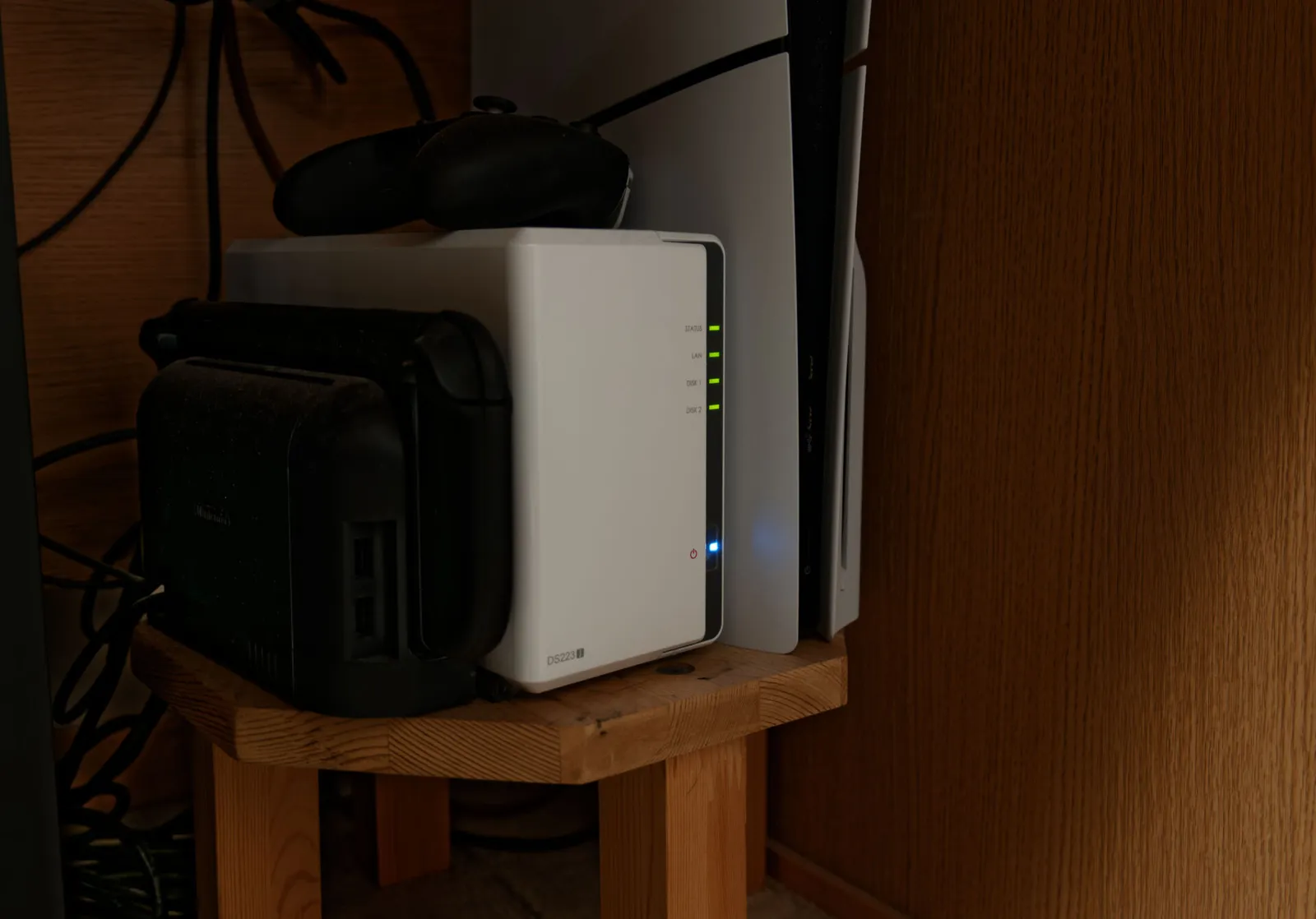 木製の台に置いたSynologyの白いNAS「DS223j」を斜めから見たところ