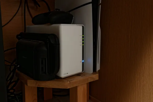 木製の台に置いたSynologyの白いNAS「DS223j」を斜めから見たところ