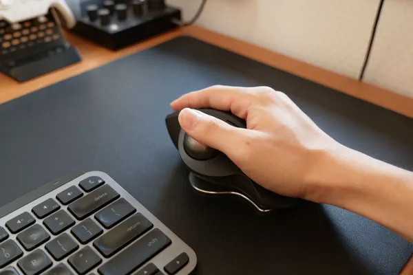 MX ERGO S に手を乗せ、親指をボールに置いて操作している様子