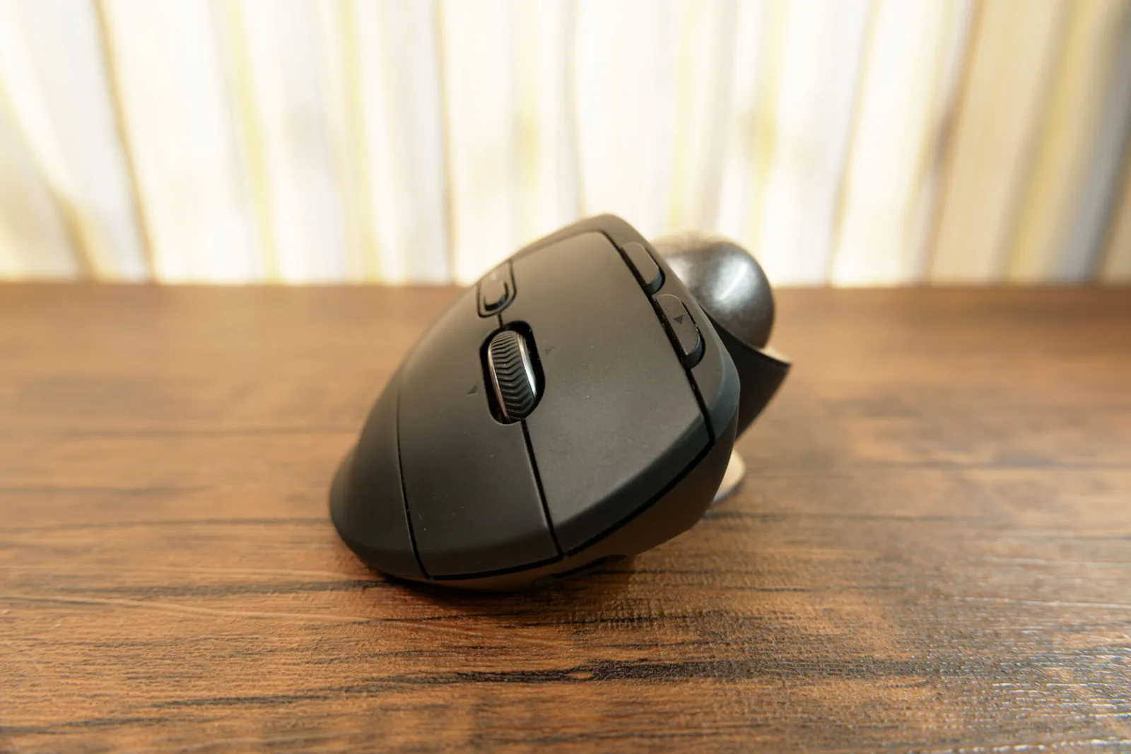 木目の机に置いた MX ERGO S を横から見た、本体の傾きとボール