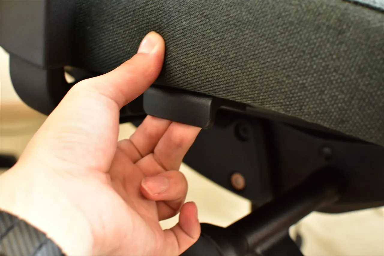 FlexiSpot C2の座面下のレバーを指で操作しているところ