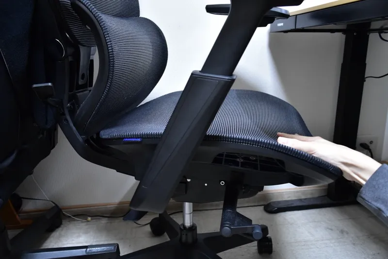 FlexiSpot C7 Airの座面下のロッキング機構に手を添えている様子