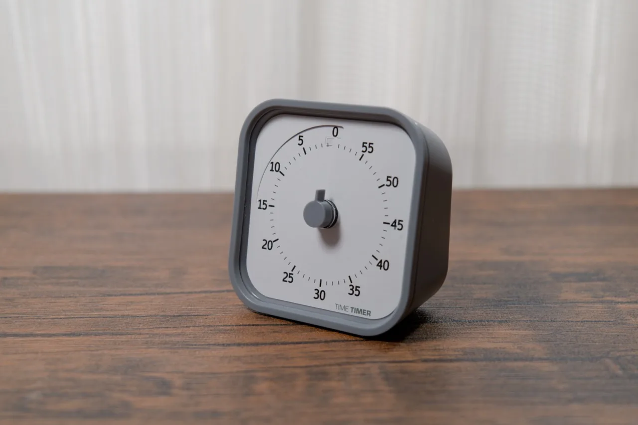 Time Timerを白いカーテンを背景に木目デスクへ斜めに置いた本体全体(残り時間0分)