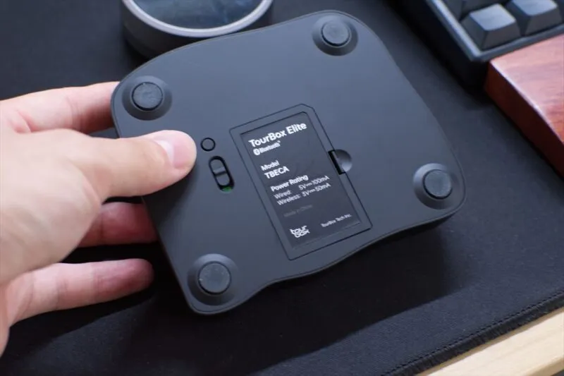 デスク上でTourBox Eliteの底面電源スイッチを指で操作している様子